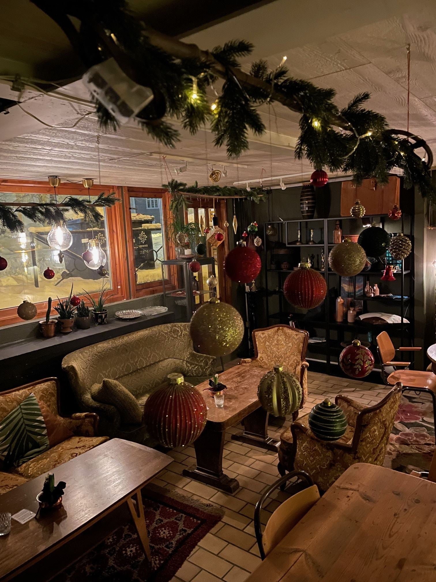 Varmt opplyst rom med julepynt, sofaer og trebord