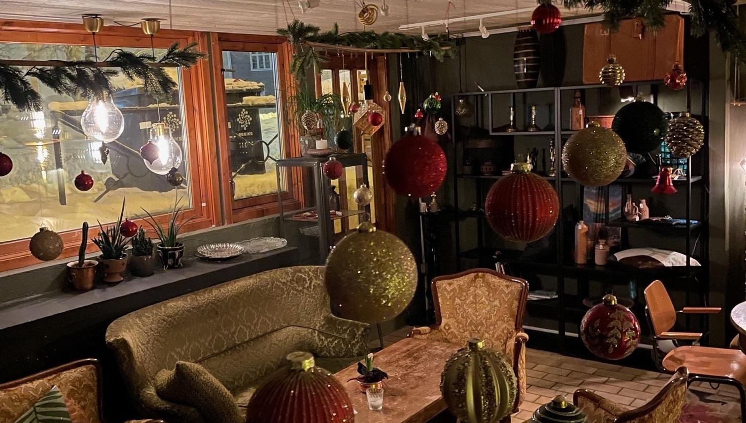 Varmt opplyst rom med julepynt, sofaer og trebord