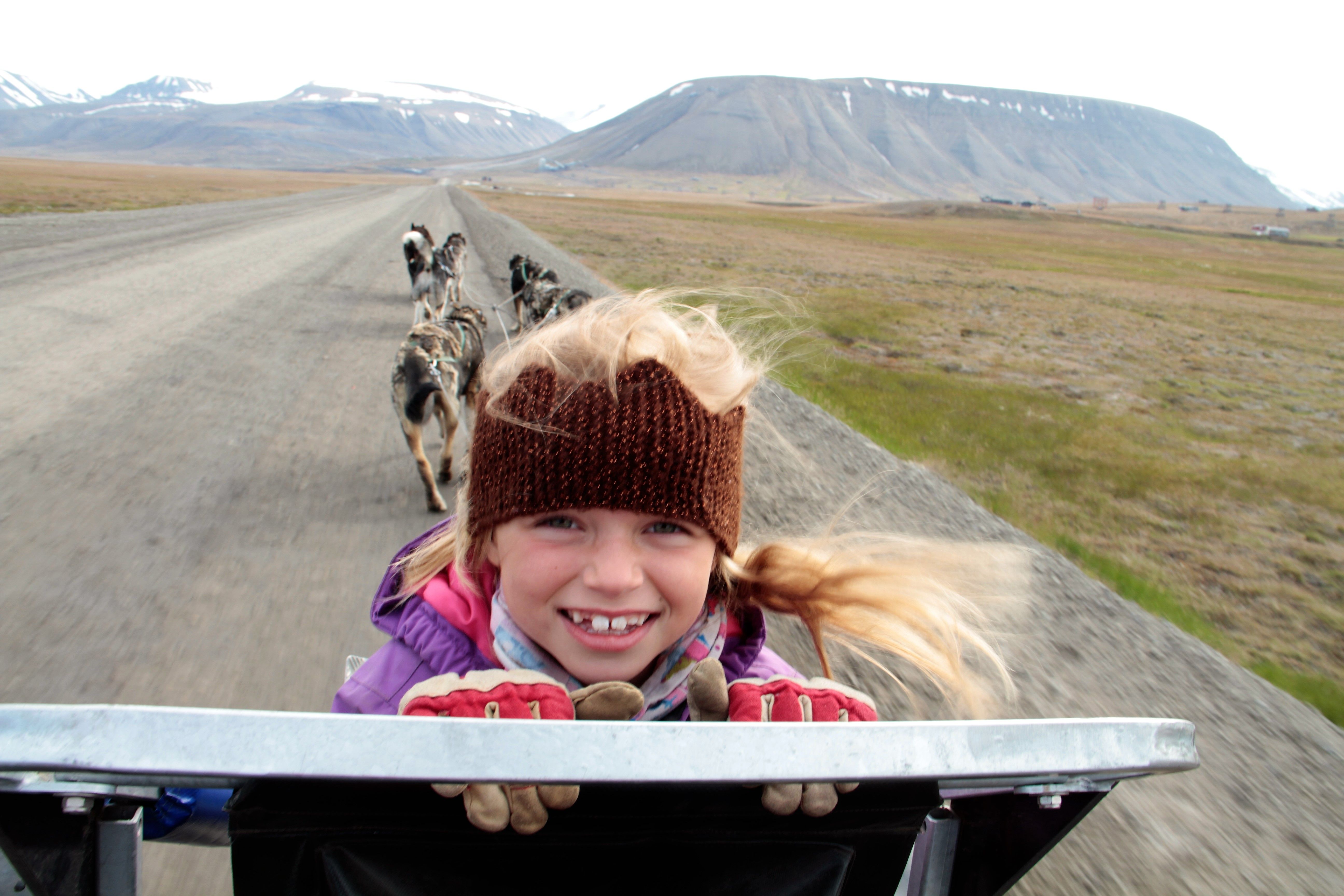 Barn sitter på hundevognen, smiler og koser seg på tur