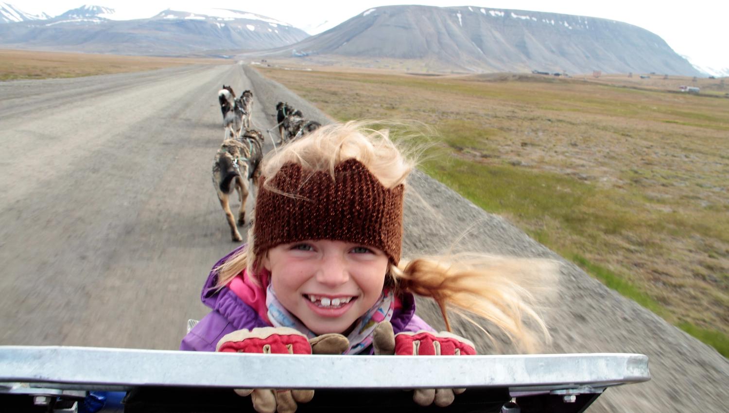 Barn sitter på hundevognen, smiler og koser seg på tur