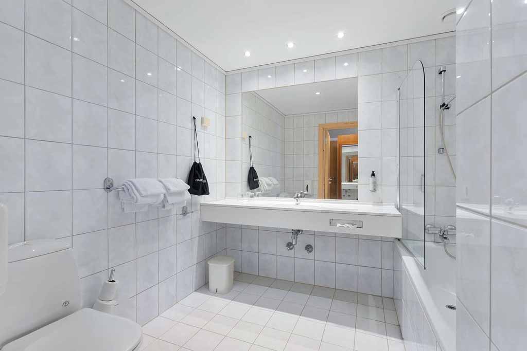 Bright bathroom with a large mirror and modern amenities at Kinsarvik Fjordhotel.
