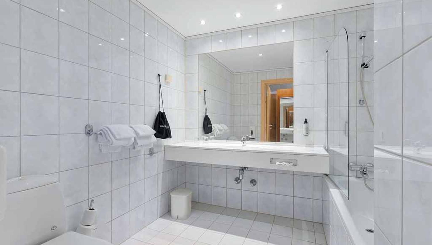 Bright bathroom with a large mirror and modern amenities at Kinsarvik Fjordhotel.