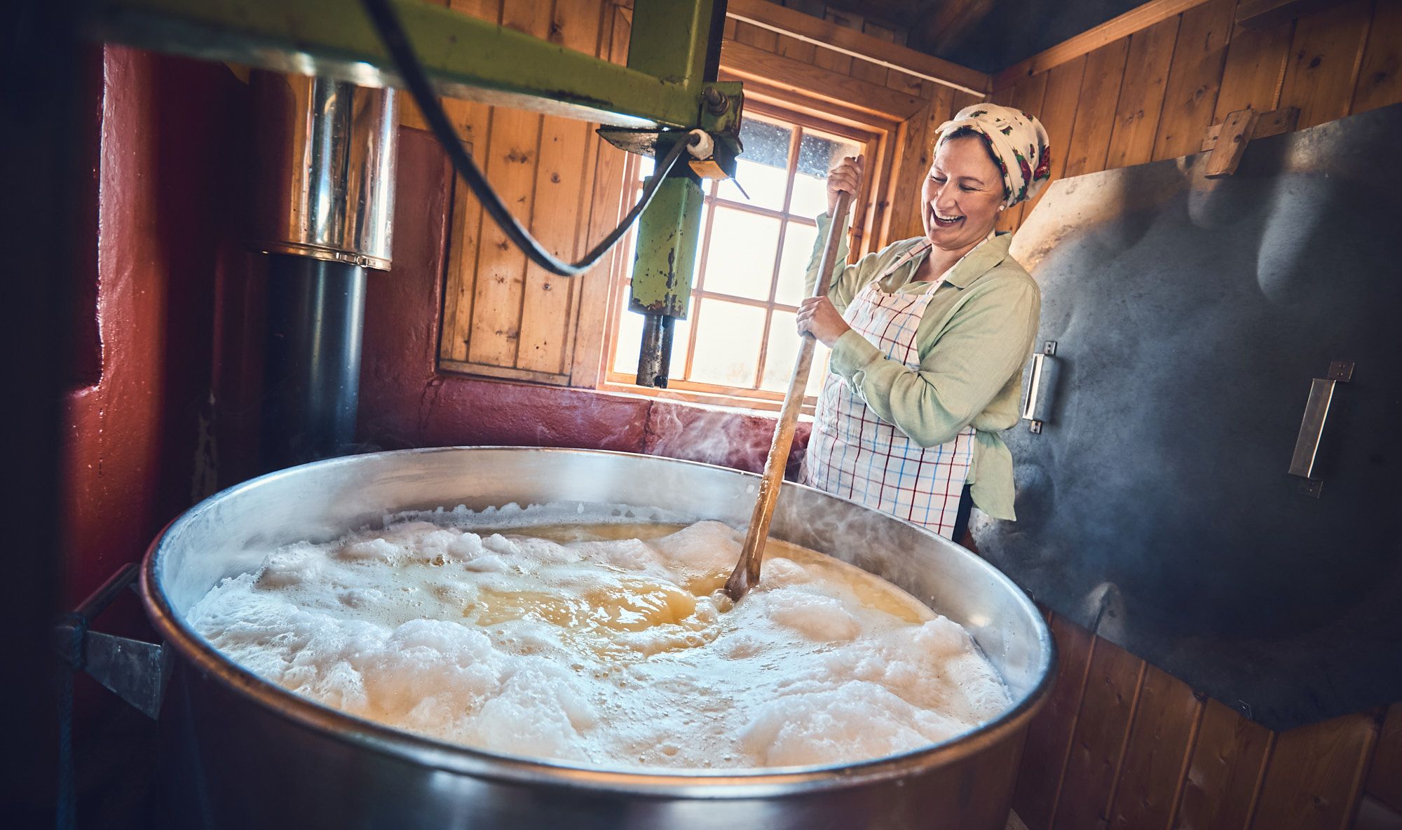 A woman stirring a big pot during the cheese-making process
