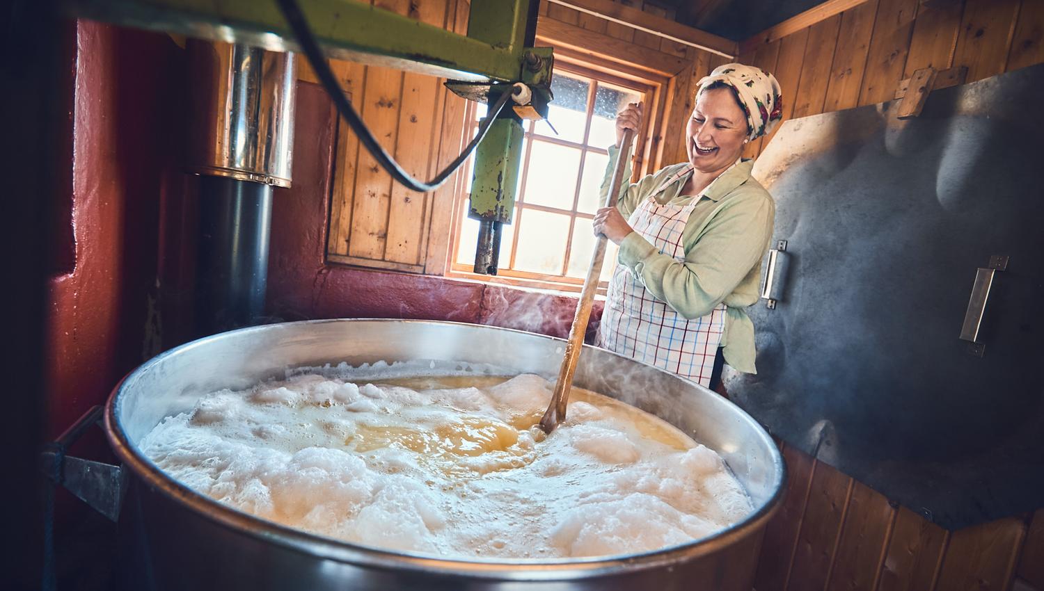 A woman stirring a big pot during the cheese-making process