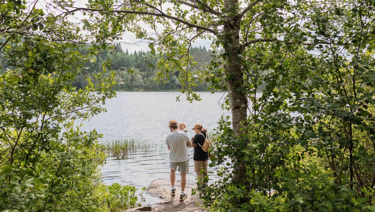 Eit par med eit lite barn ser utover Gullfiskvatnet i Hardanger, omringa av frodig vegetasjon og ein vakker innsjø.