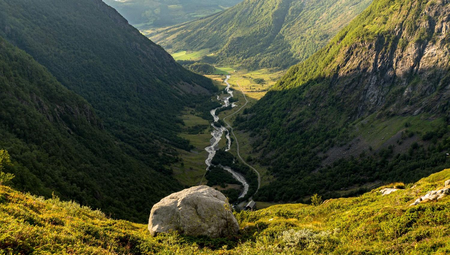 Utsyn ned i Hattebergsdalen der elva slyngjer seg mellom bratte fjellsider og grøne fjellbeiter.