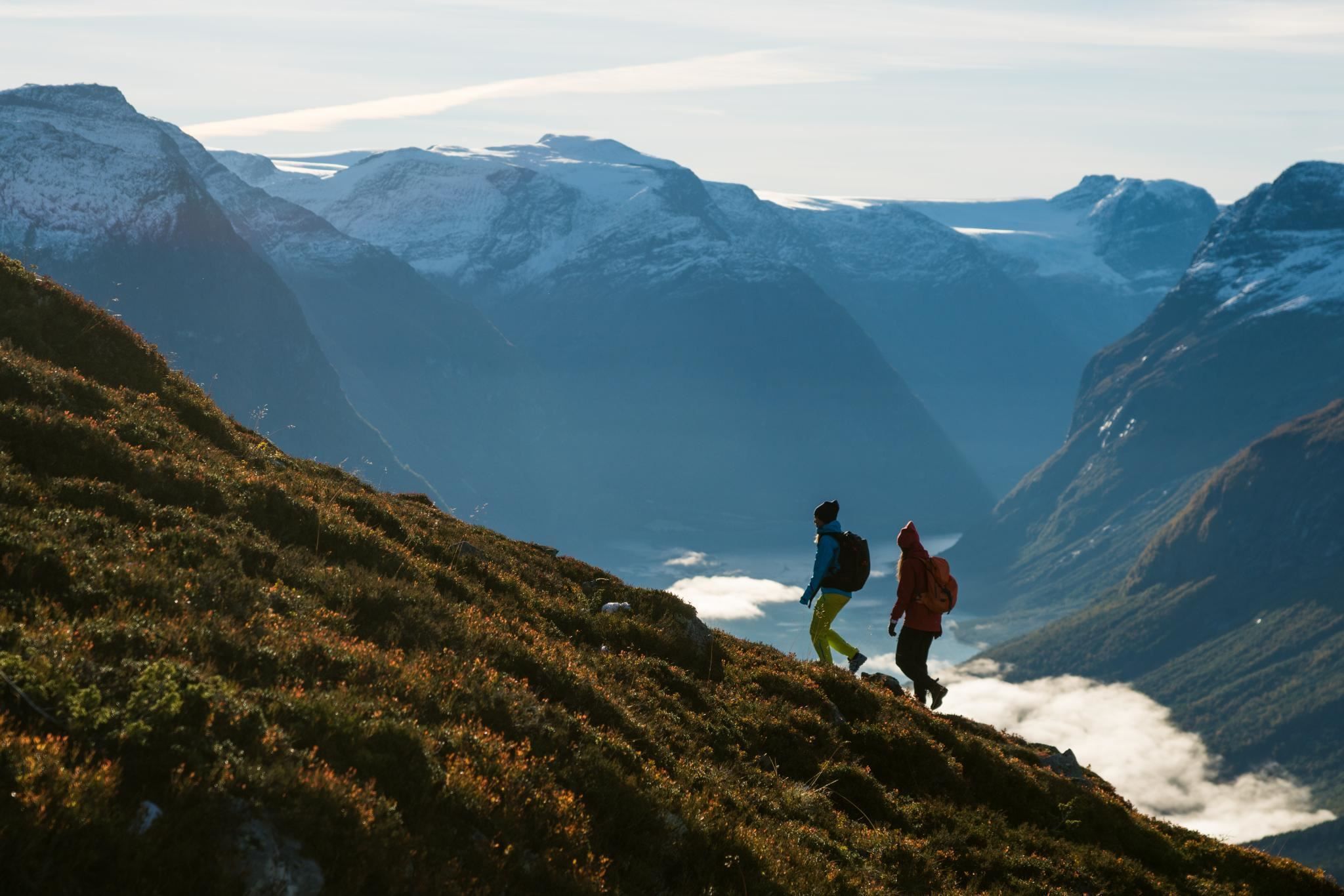 Hikers on a rocky mountain trail at Hoven, surrounded by dramatic mountain scenery and views of the fjord.