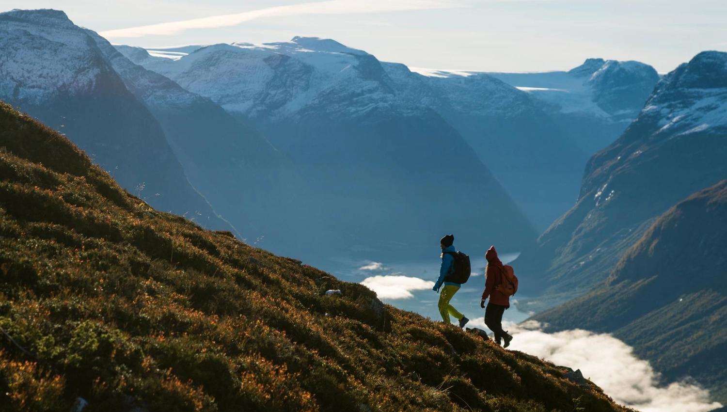 Hikers on a rocky mountain trail at Hoven, surrounded by dramatic mountain scenery and views of the fjord.