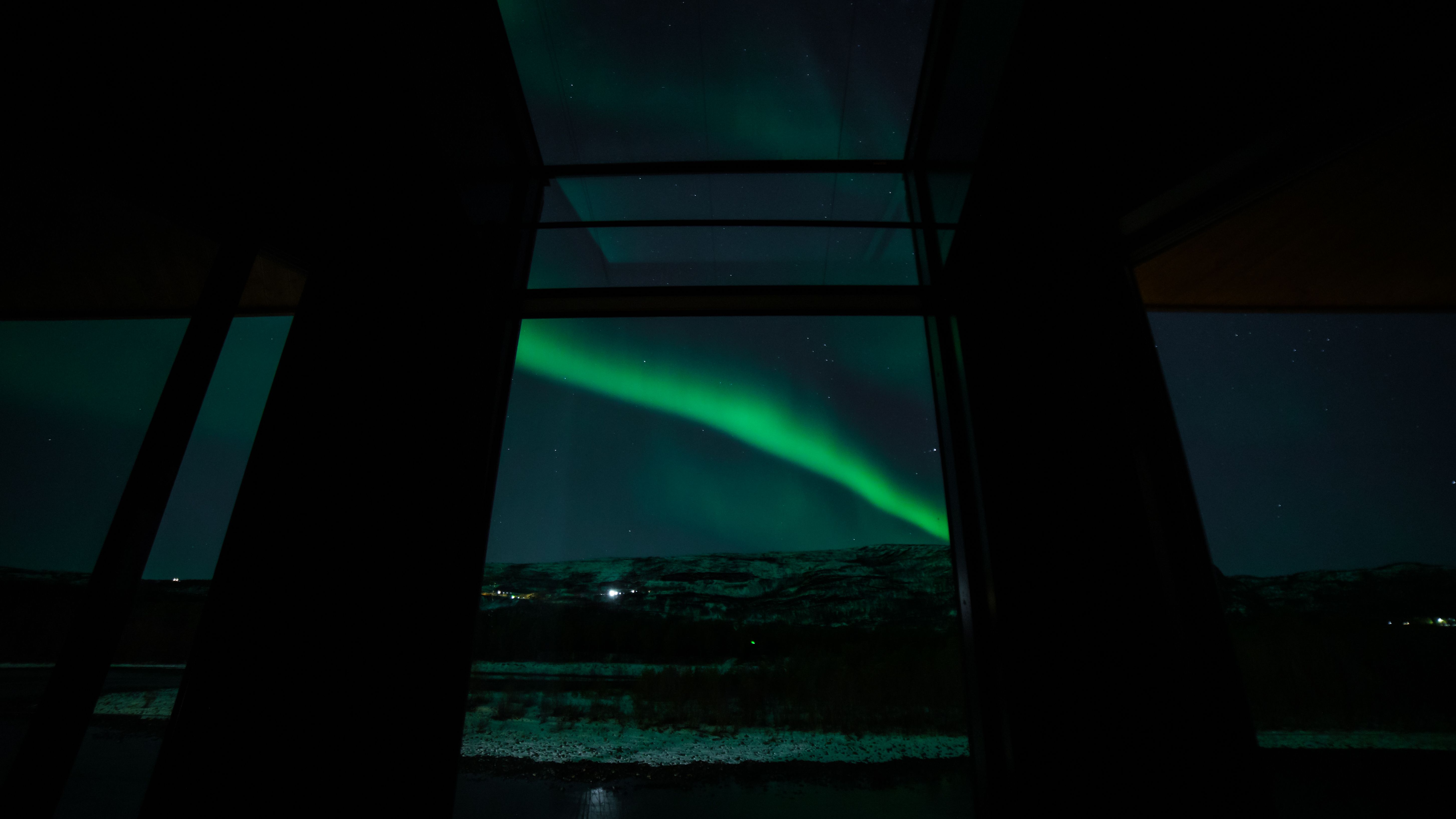 Aurora borealis visible through large windows, snow-covered landscape below.