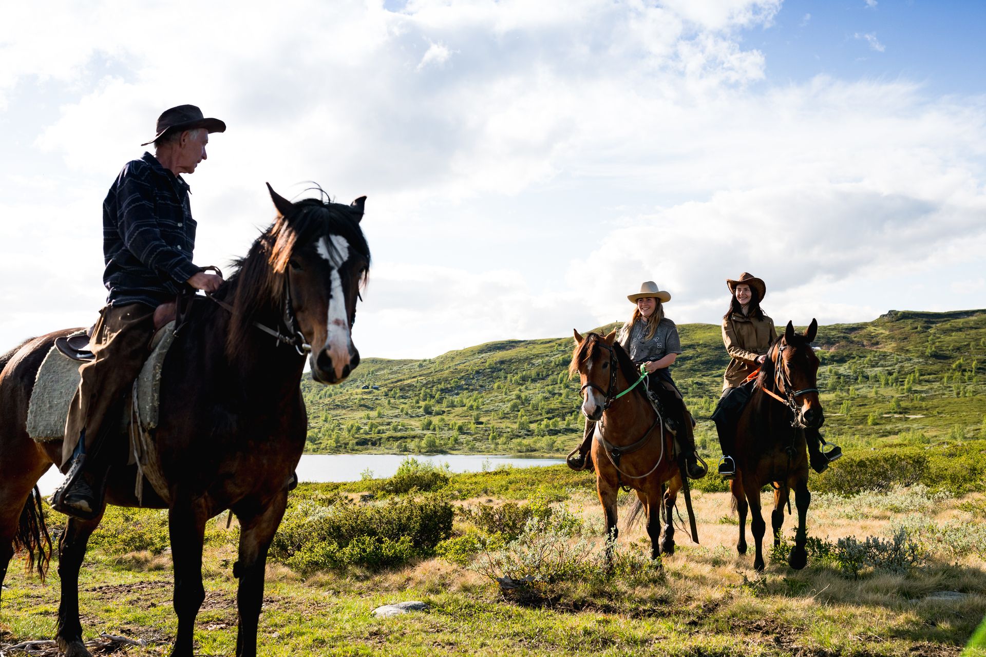 On a horseback riding tour into the mountains, surrounded by green landscape and a small mountain lake. 