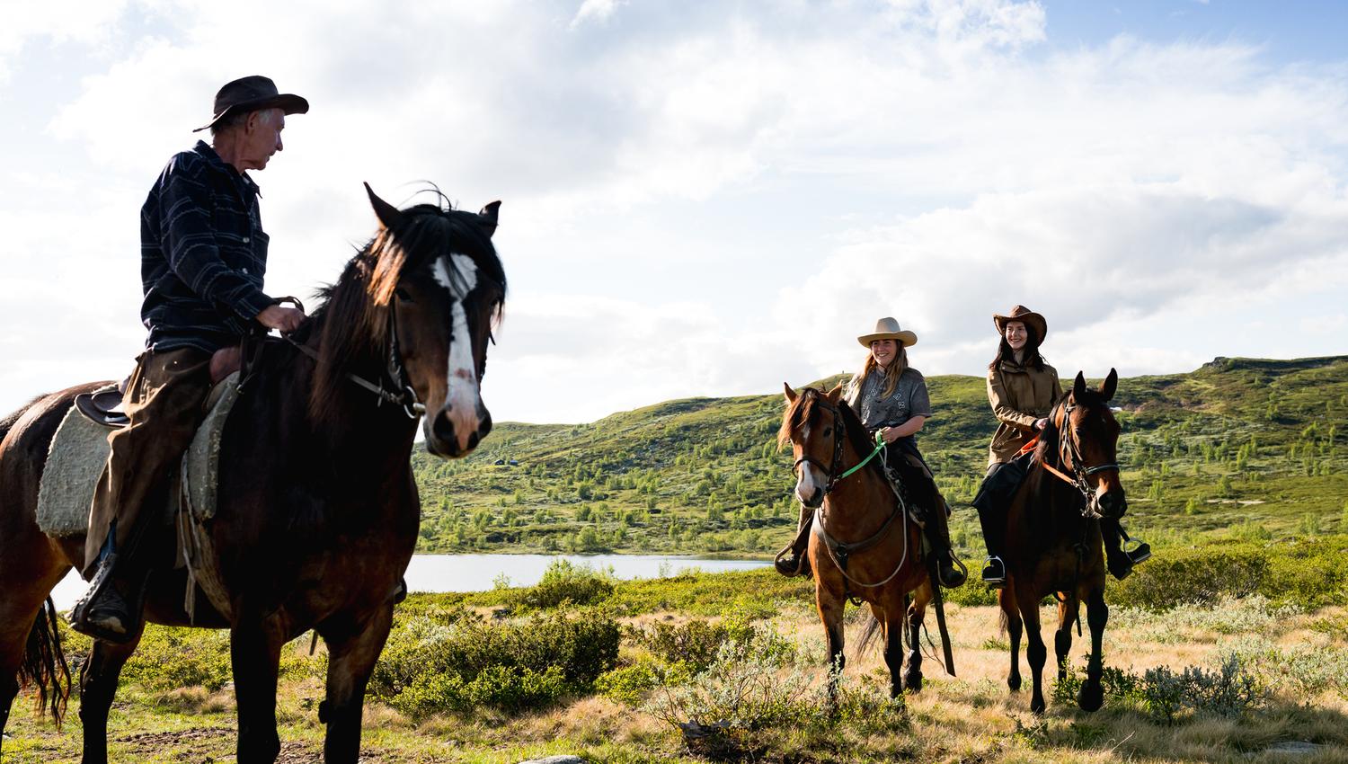 On a horseback riding tour into the mountains, surrounded by green landscape and a small mountain lake.