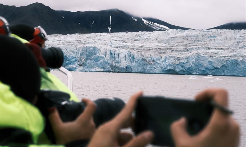 Bilde av passasjerer som fotograferer isbre i bakgrunnen