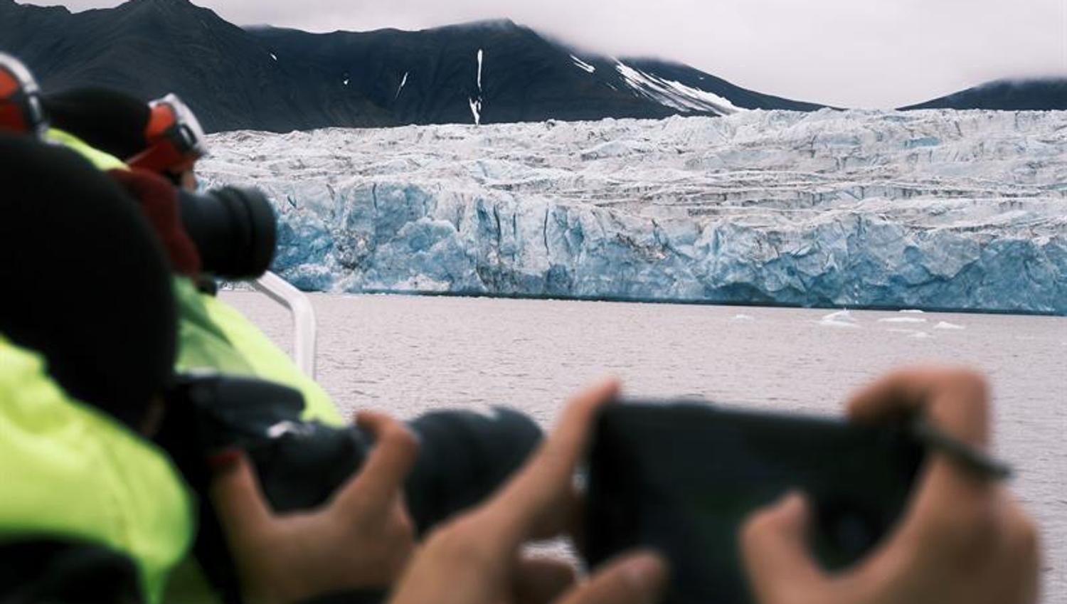 Bilde av passasjerer som fotograferer isbre i bakgrunnen