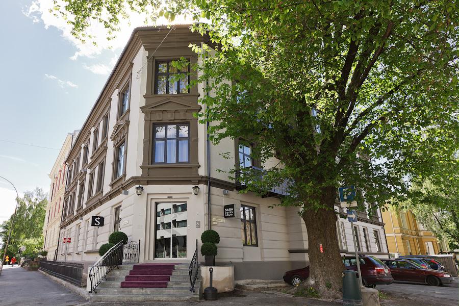Fasade med tre etasjer. Grønt tre, blå himmel.Saga Hotel Oslo. Foto