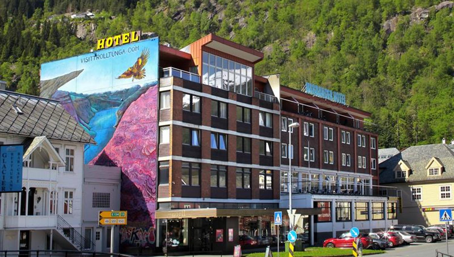 Hardanger Hotel in Odda with colourful mural art and mountains in the background.