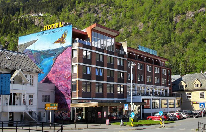 Hardanger Hotel in Odda with colourful mural art and mountains in the background.