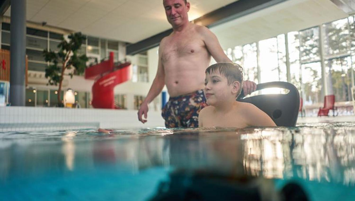 father and son in a wheelchair in the swimming pool in Skien leisure park