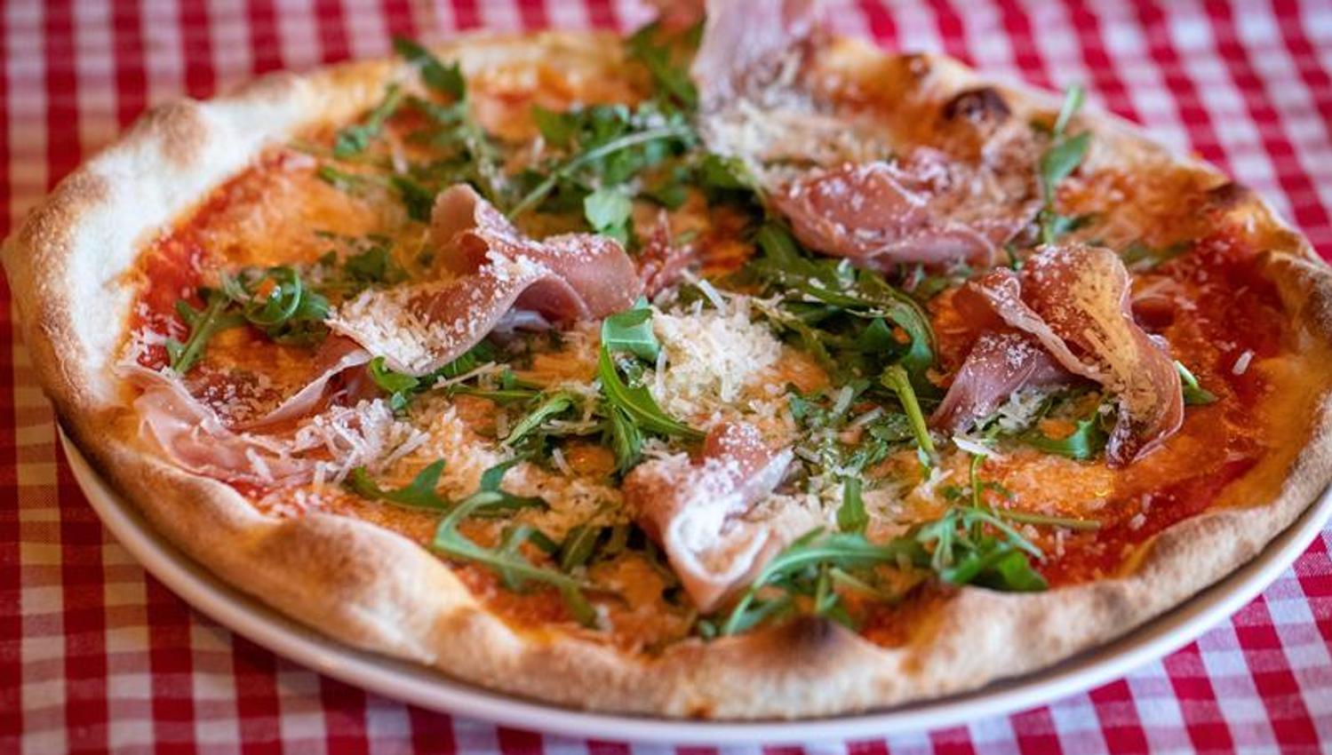 Detalj av pizza på rødrutete duk.
