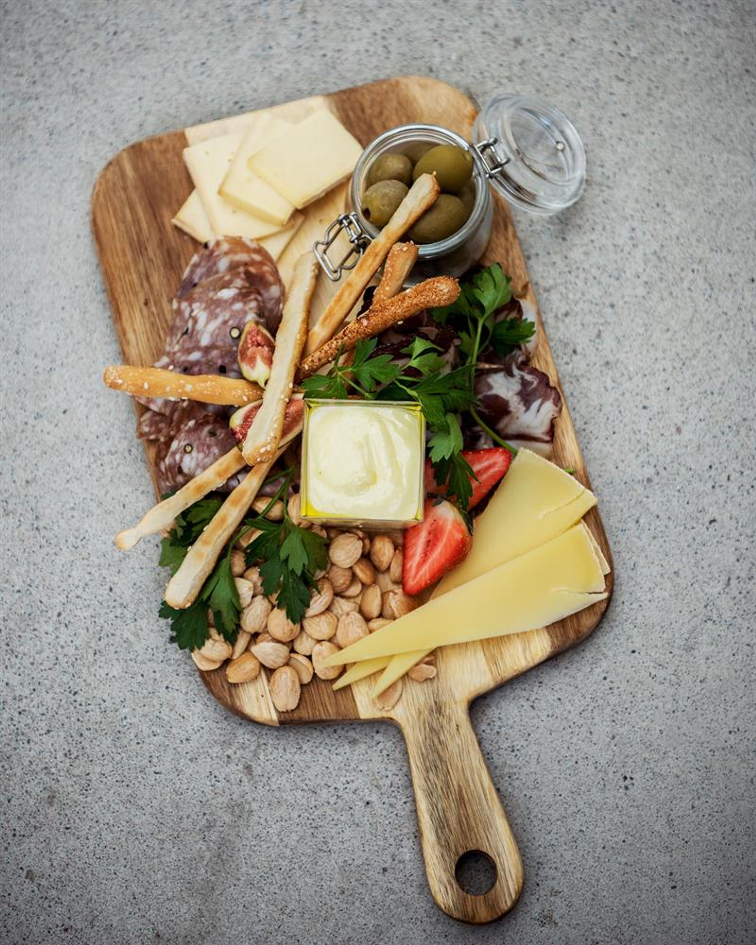 Tapas platter with cheese, cured meats, olives, nuts and vegetables served on a wooden board from Matlykke.