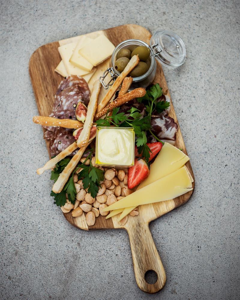 Tapas platter with cheese, cured meats, olives, nuts and vegetables served on a wooden board from Matlykke.