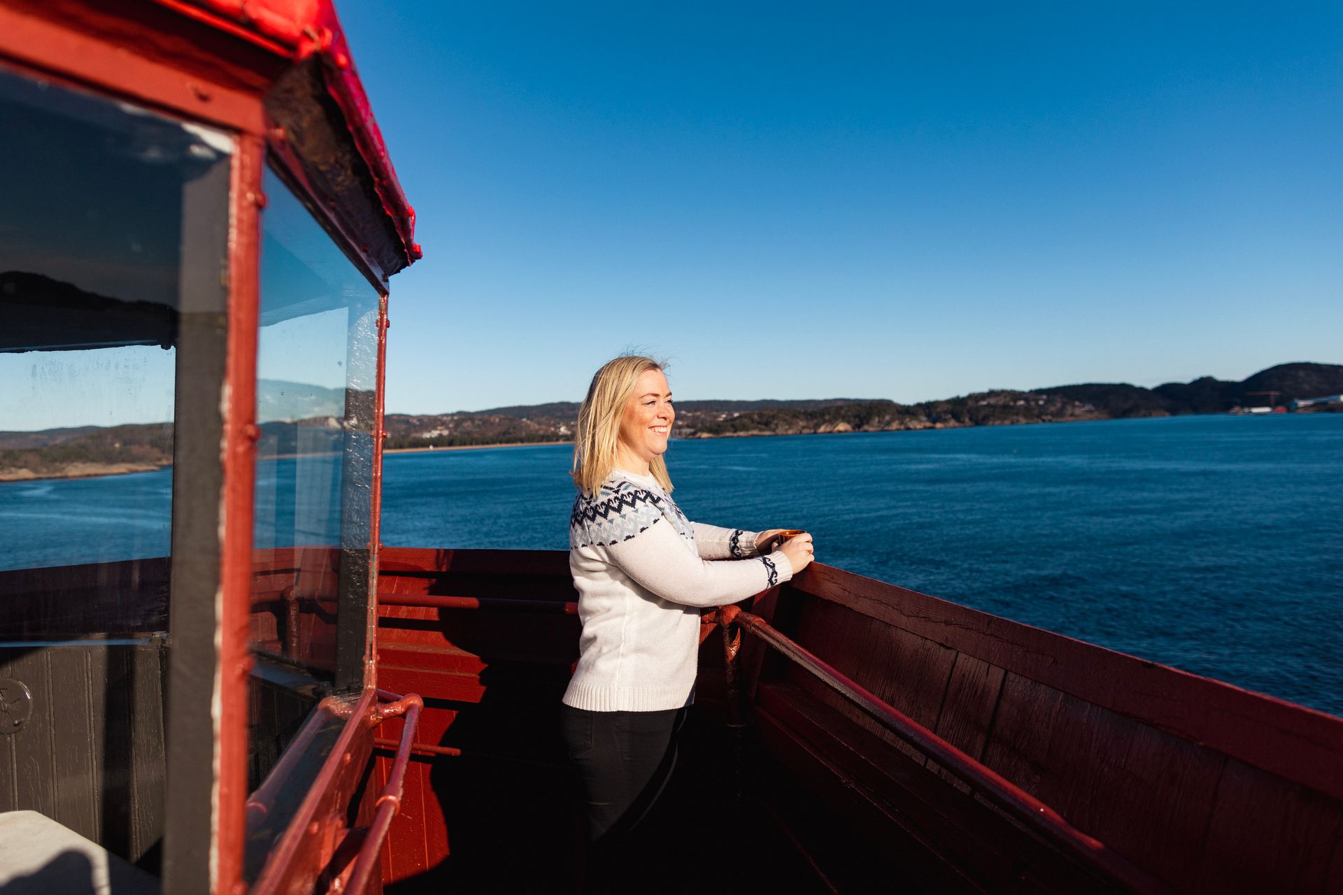 A woman standing at the top of the Hatholmen Lighthouse, looking out over the sea