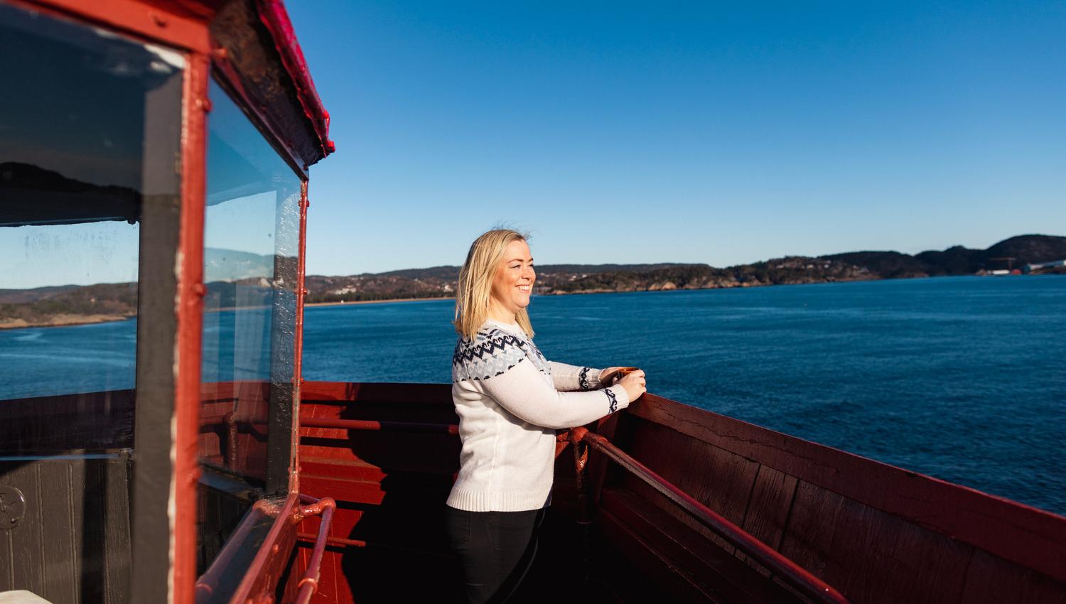 A woman standing at the top of the Hatholmen Lighthouse, looking out over the sea