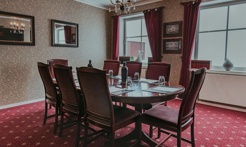 A meeting room with a red carpet and chairs around a meeting table
