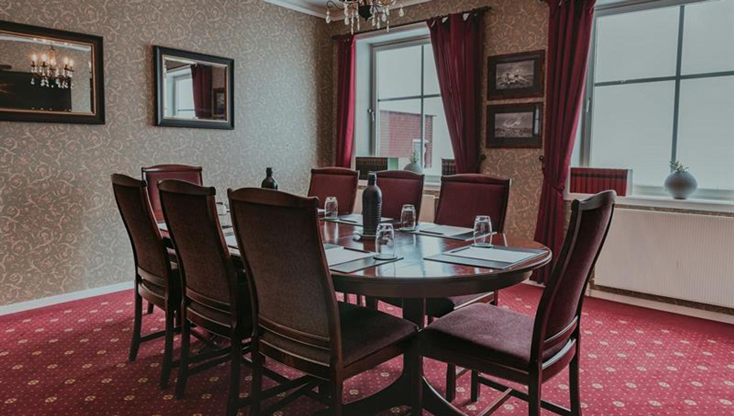 A meeting room with a red carpet and chairs around a meeting table