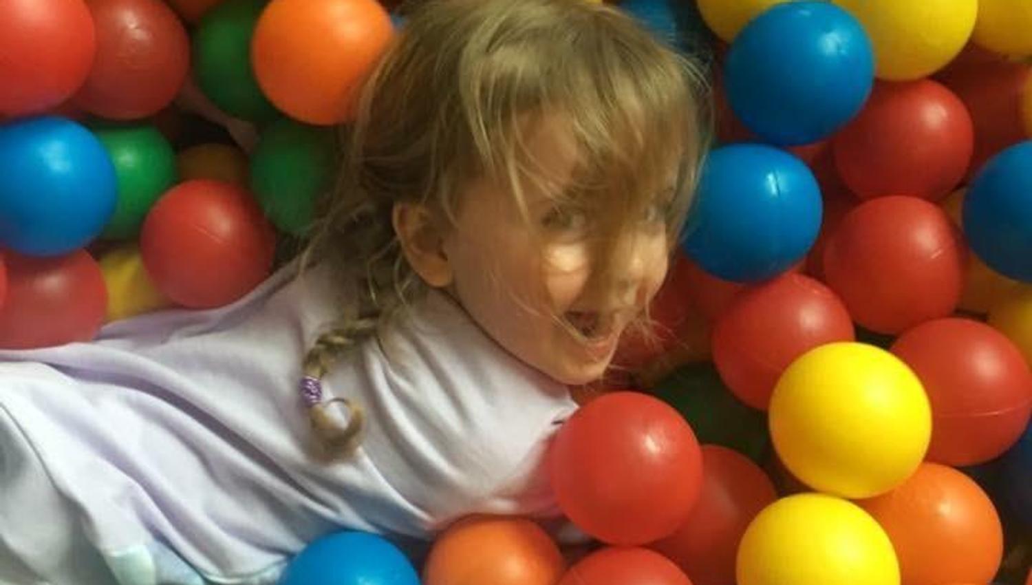 Little girl playing in ball pit