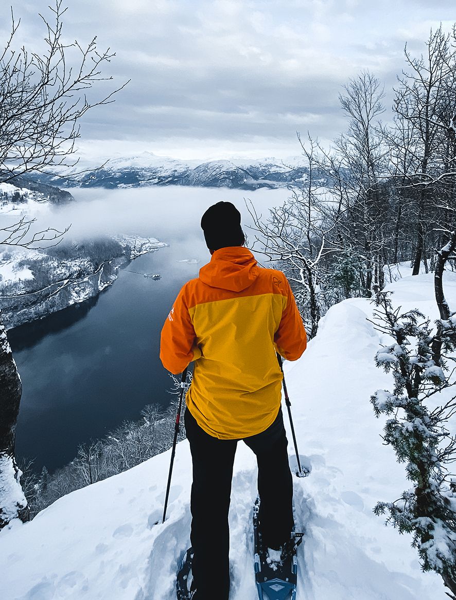 A snowshoer enjoys the view of the Hardangerfjord from the trail edge.
