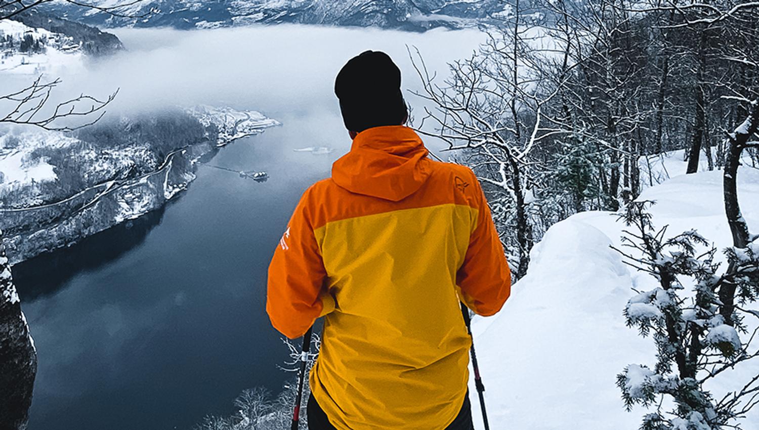 A snowshoer enjoys the view of the Hardangerfjord from the trail edge.