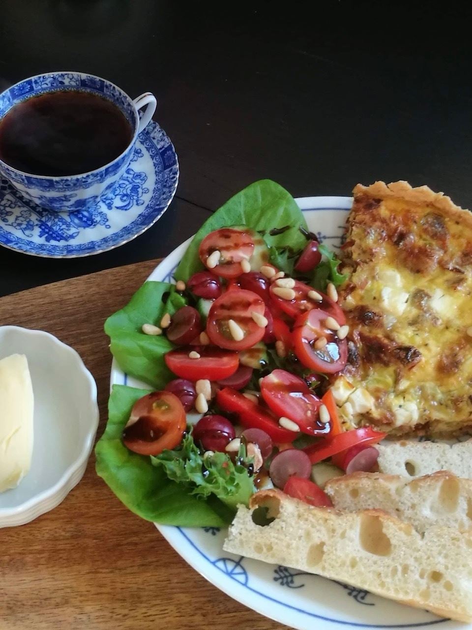 Tallerken med quiche, salat, brød og kaffe på trebord