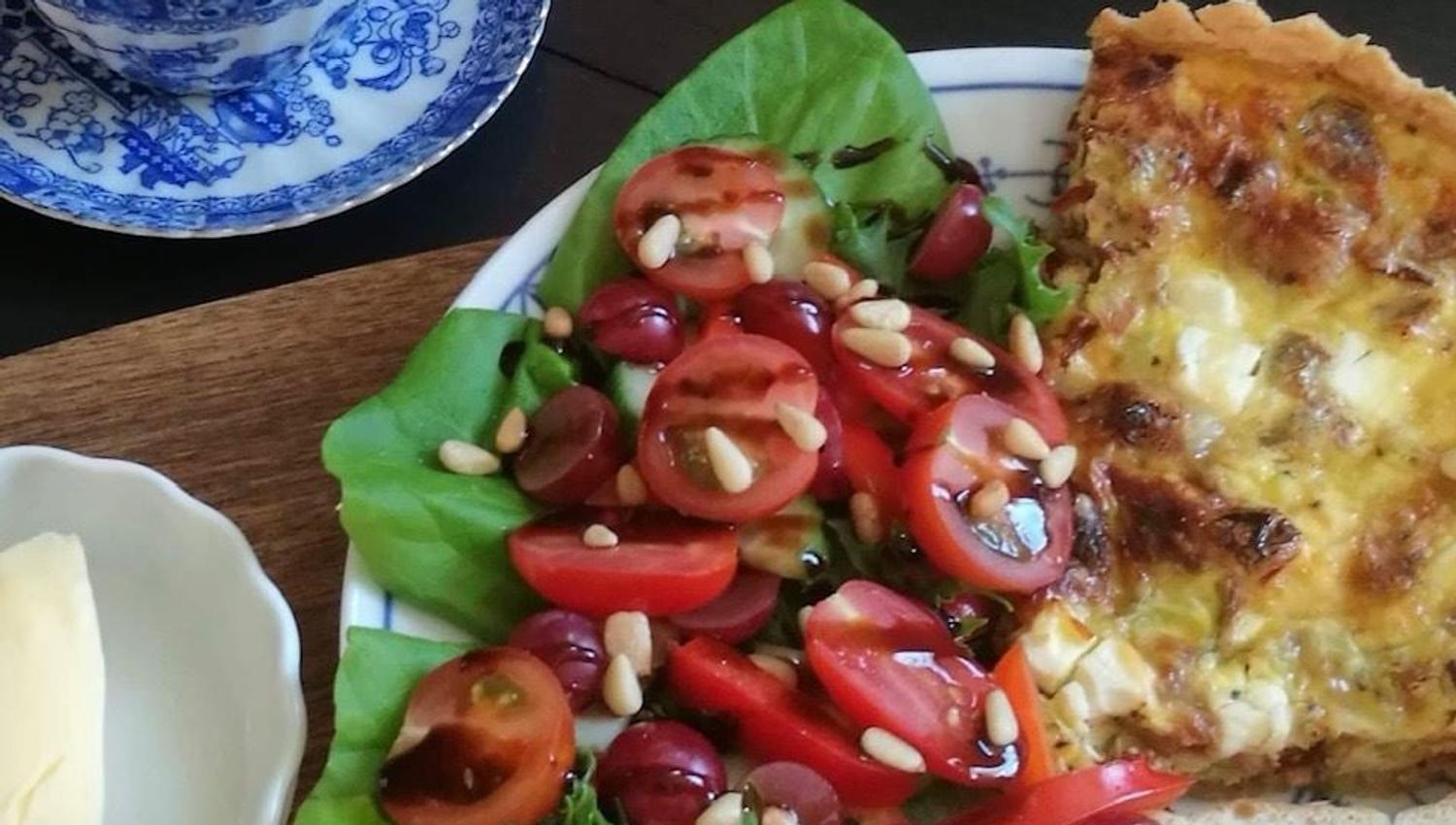 Tallerken med quiche, salat, brød og kaffe på trebord