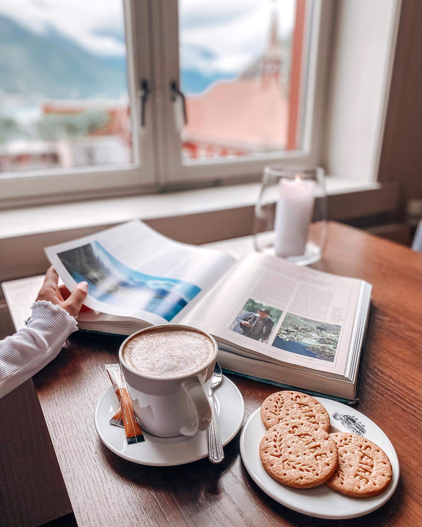 Coffee and cookies and a person looking in a book. 