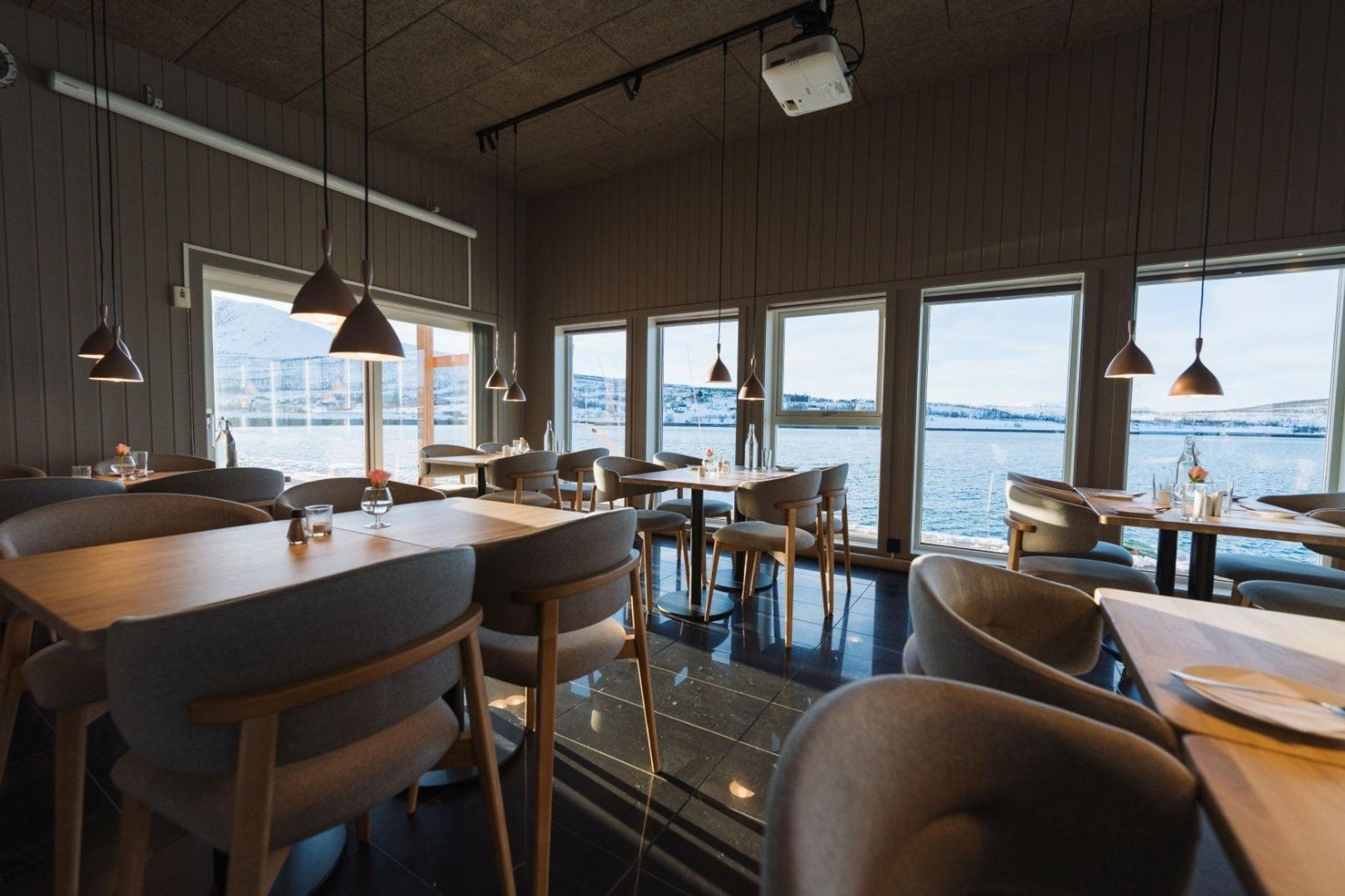 The restaurant with table and chairs, panorama windows with a fjord view