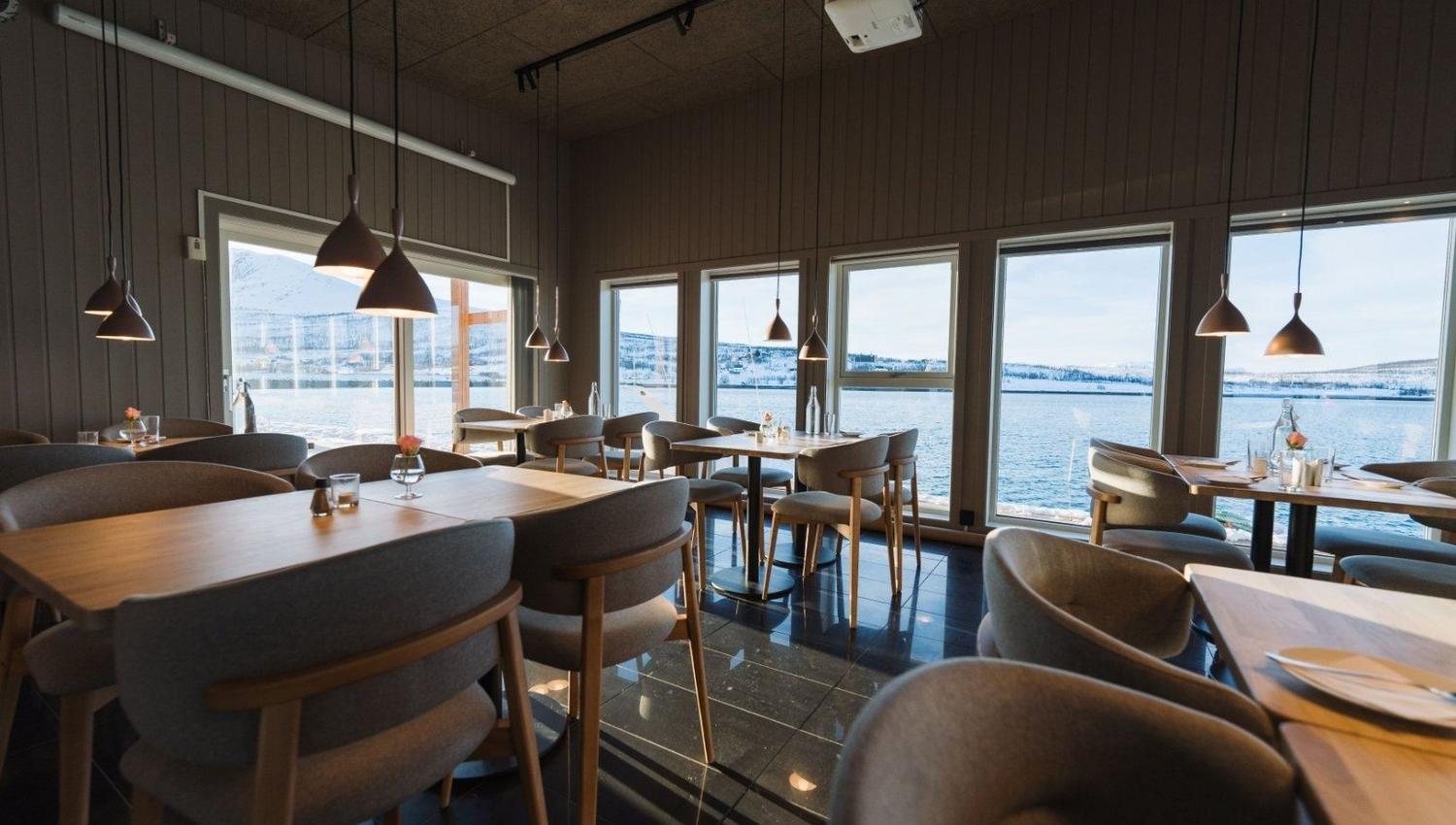 The restaurant with table and chairs, panorama windows with a fjord view