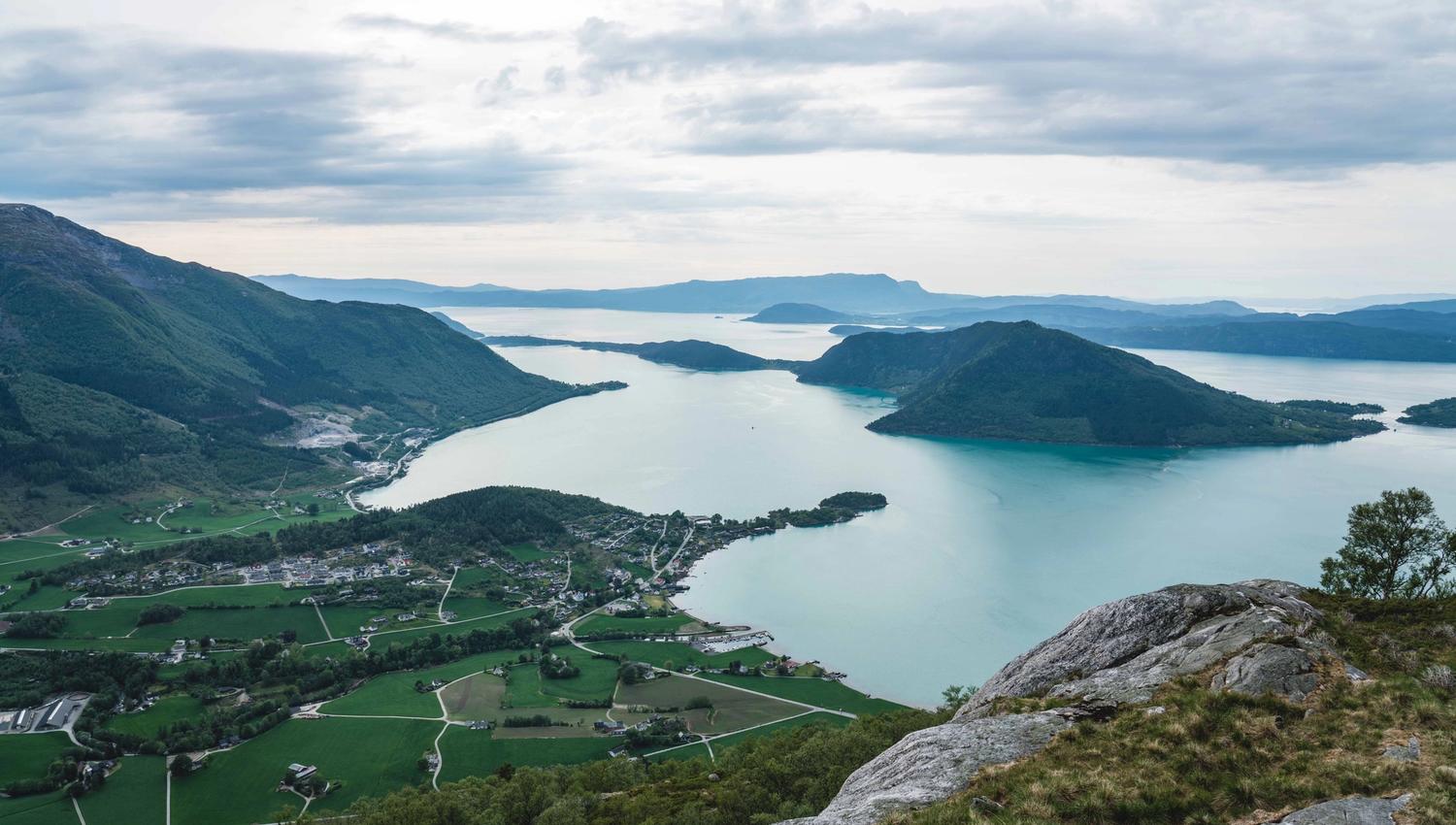 Panoramic view from Kviteggjo overlooking the Hardangerfjord, green farmlands and islands in soft afternoon light.