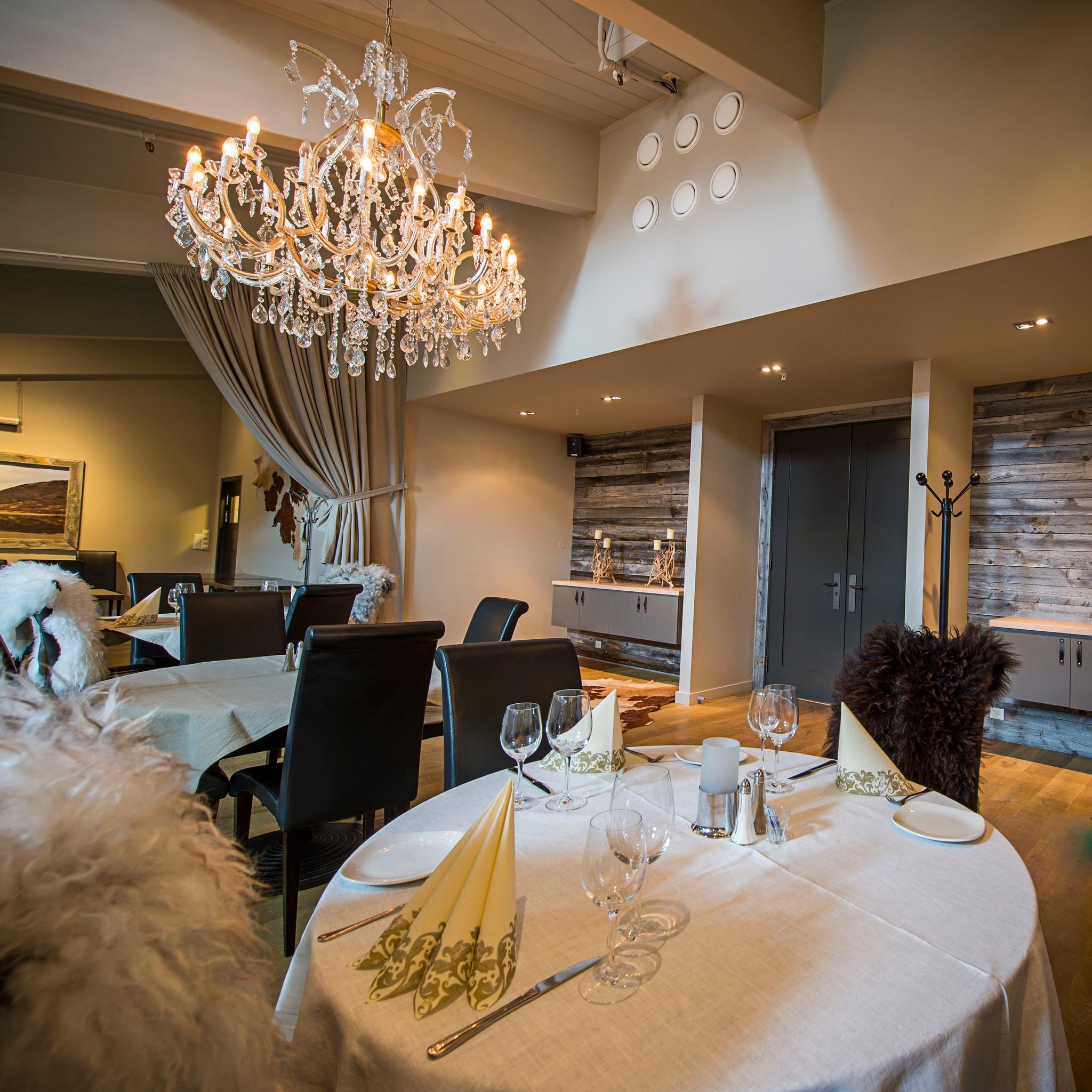 Decorated for fine dining with white table cloth, wine glasses and nice napkins. Chandelier in the ceiling