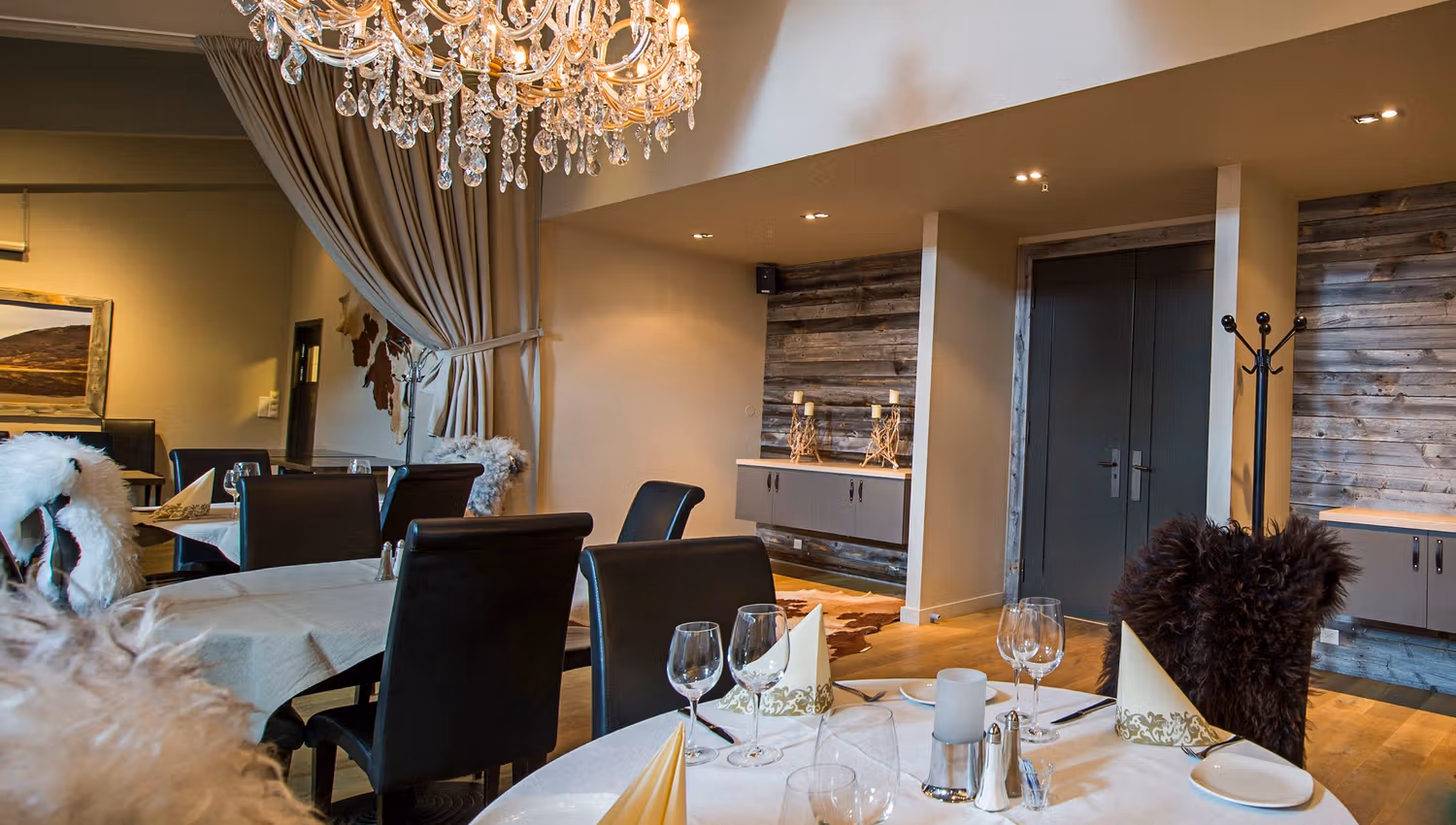 Decorated for fine dining with white table cloth, wine glasses and nice napkins. Chandelier in the ceiling