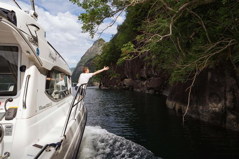 A guest enjoys the fjord cruise aboard Pilagutt as the boat navigates through narrow fjords with spectacular scenery.