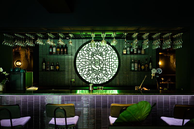 Bar counter with dark tiles and a green lamp in the background