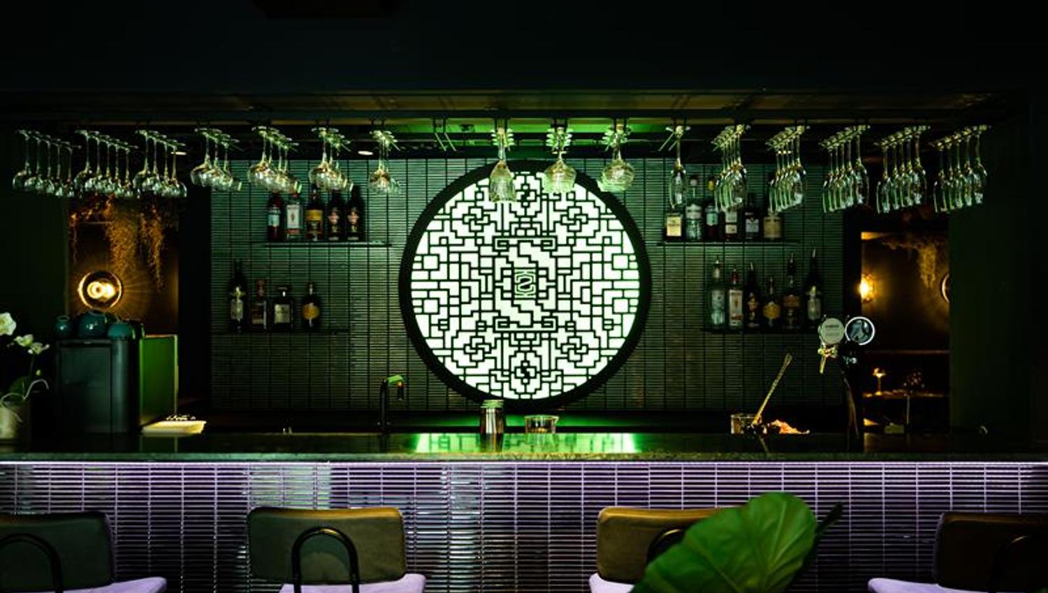 Bar counter with dark tiles and a green lamp in the background