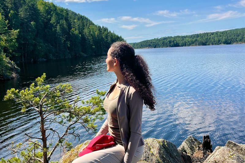 Girl sitting by a lake with the forest in the background