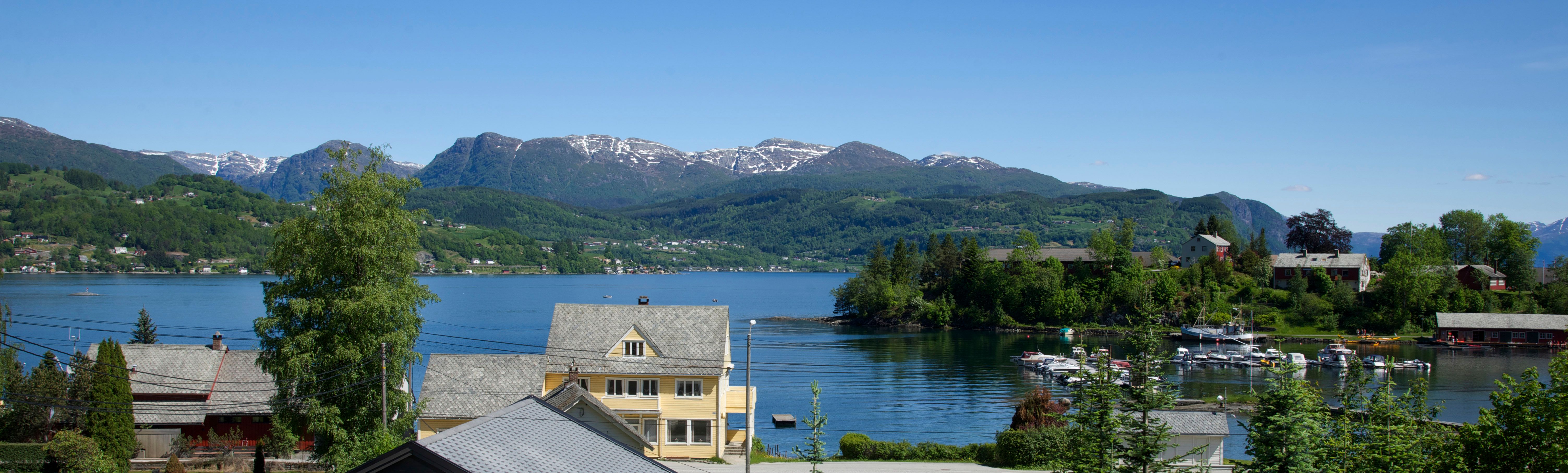 Panoramic view of the Hardangerfjord with mountains and villages, seen from Vågen Rom og Hytteutleige.