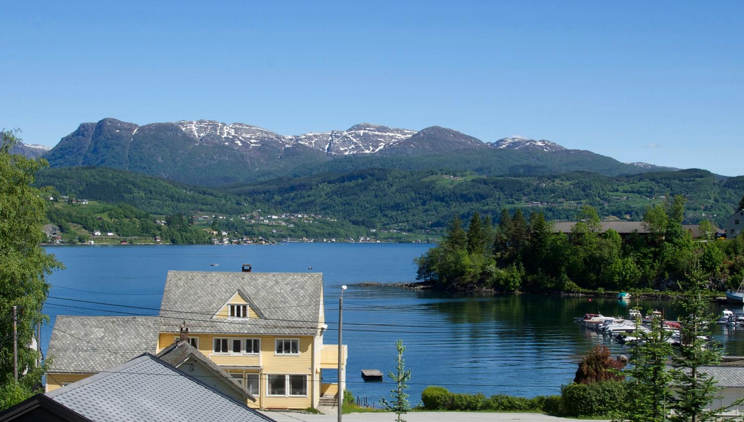 Panoramic view of the Hardangerfjord with mountains and villages, seen from Vågen Rom og Hytteutleige.