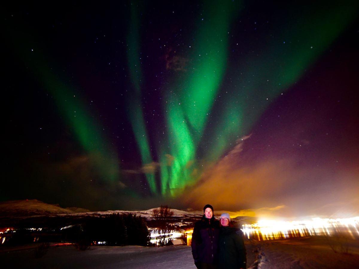 Two guests posing under the northern lights