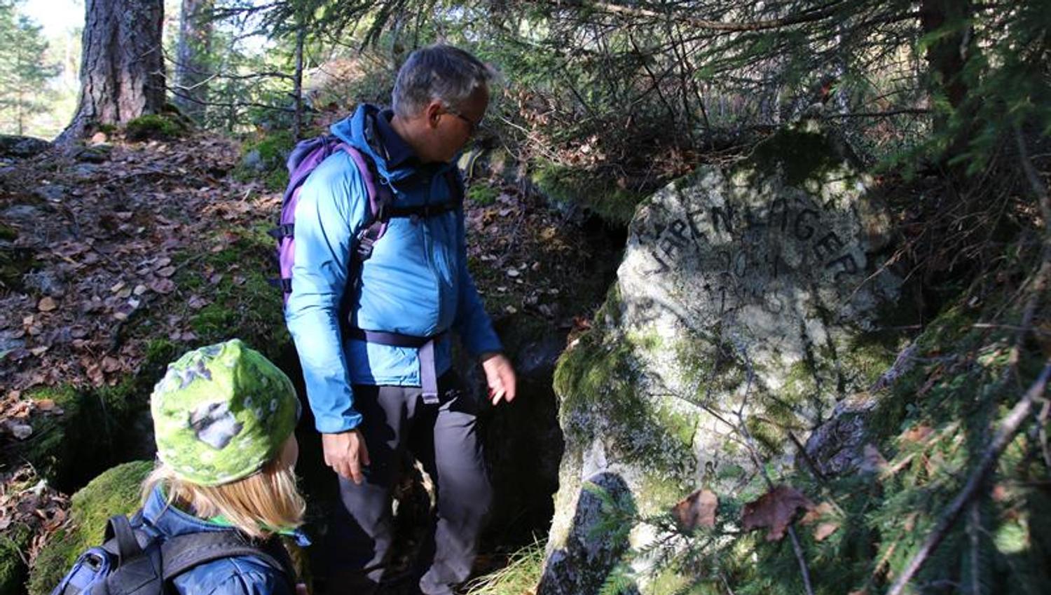 Voksen og barn ser på steinen med innskrift