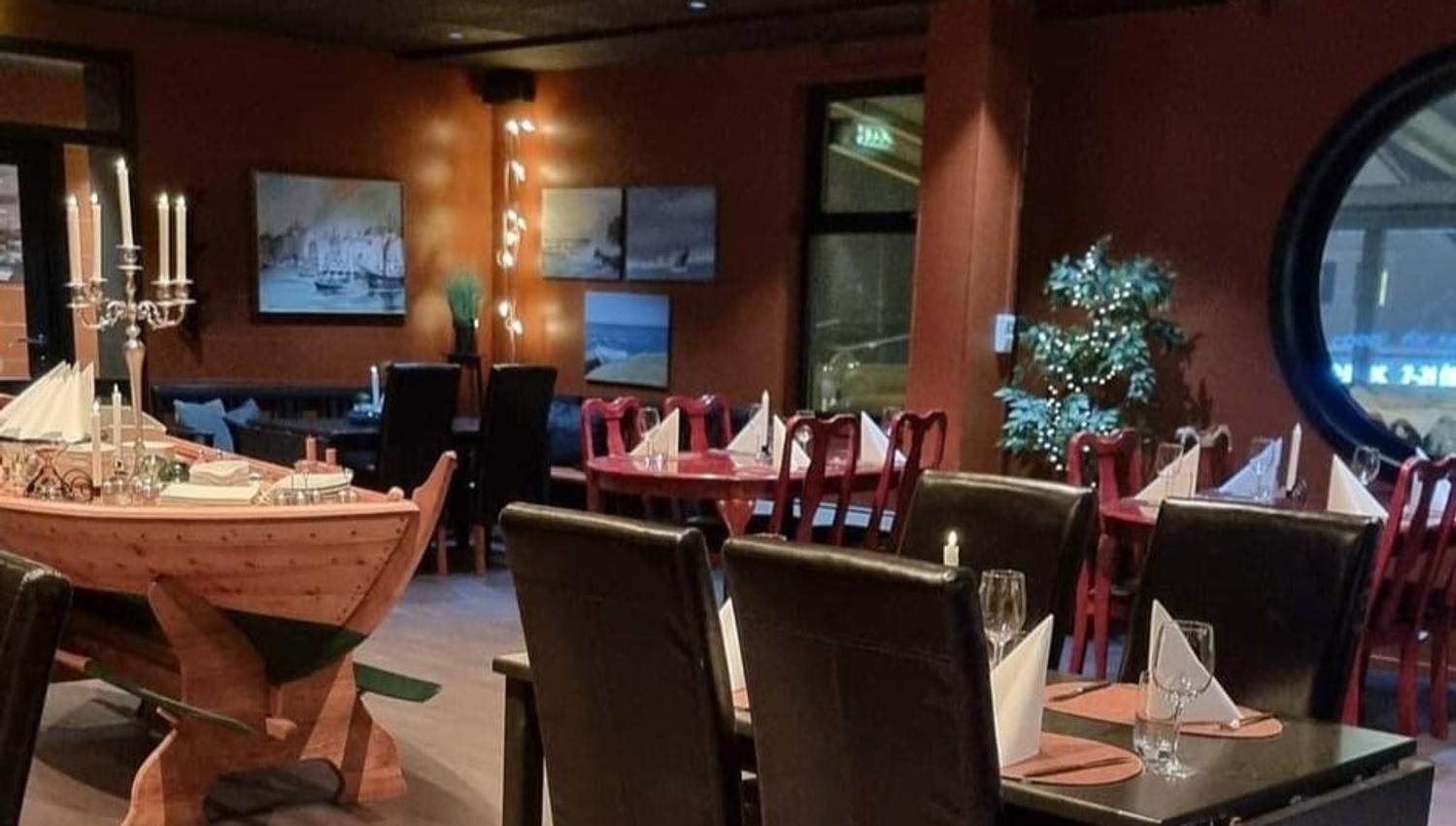 Interiørbilete av restauranten hos Gjøa Sjømat, med ein maritim stil og koselege oppdekka bord klare for gjestar.