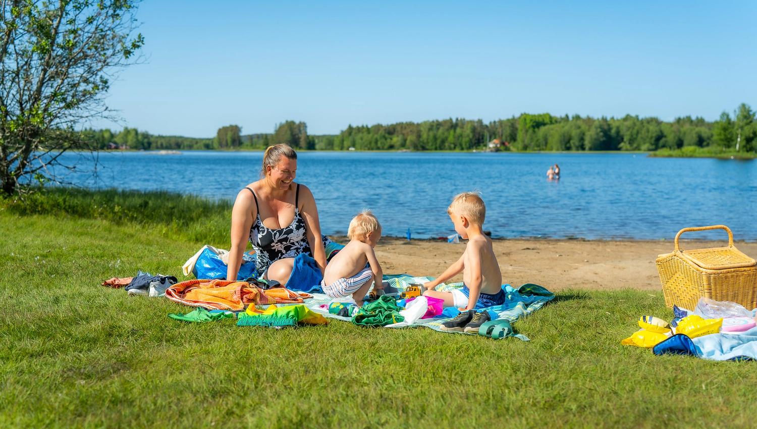 Noen som koser seg på gresset og noen bader i bakgrunnen
