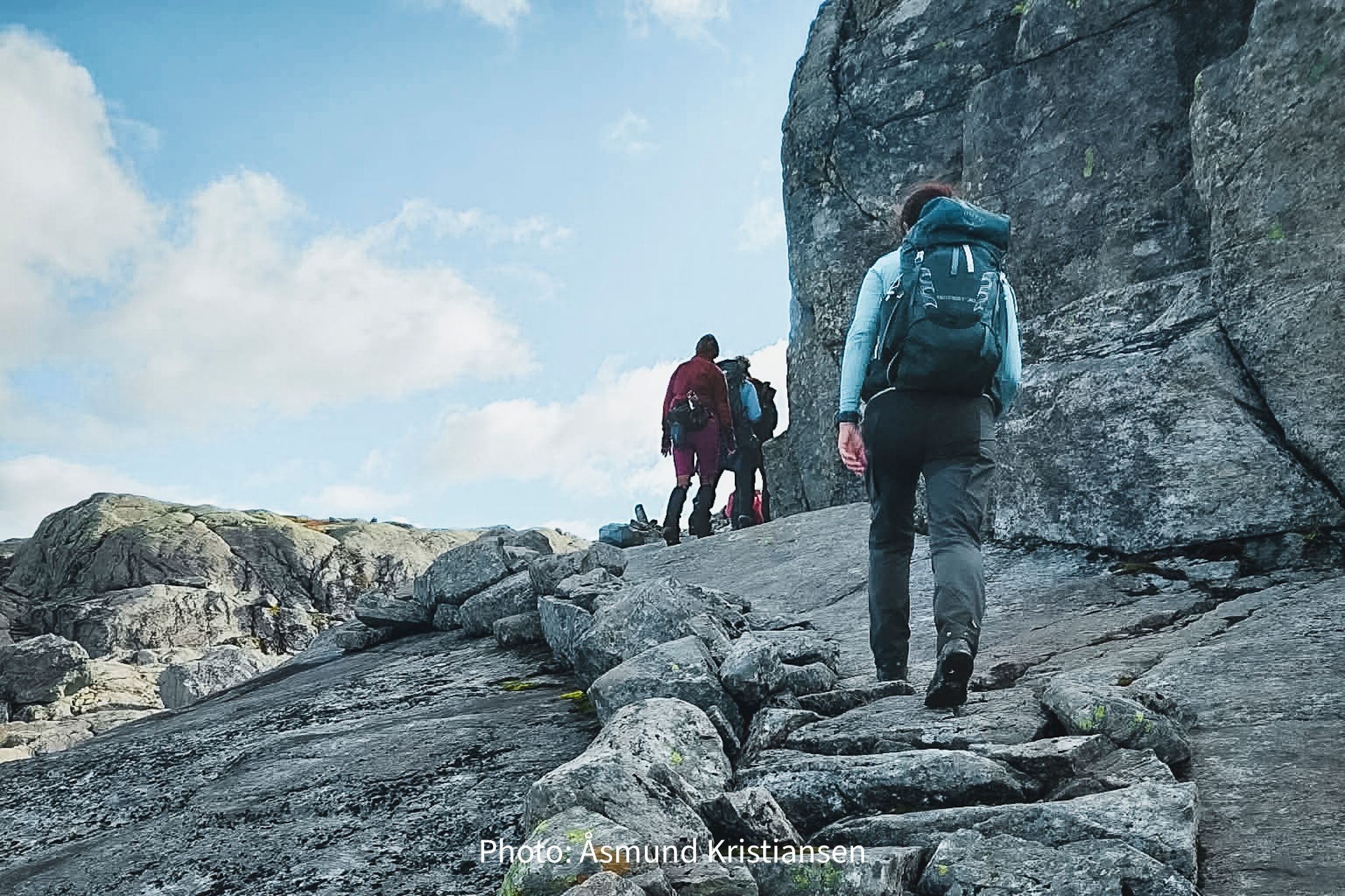 Mountain hikers crossing bare rock terrain in Hardanger, Norway, surrounded by open landscapes

